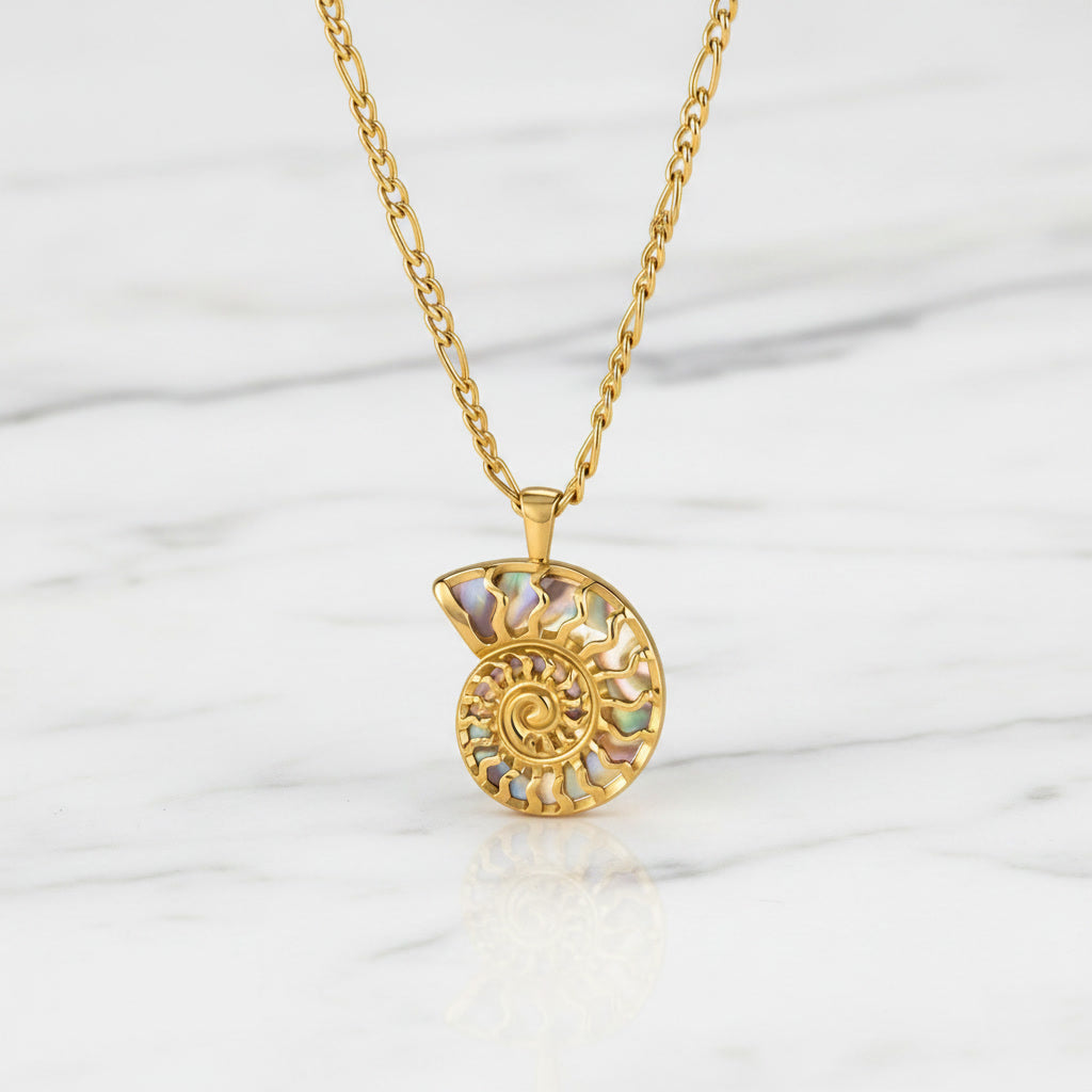 Esta Abalone luxury gold necklace displayed on a white marble surface, showcasing its elegant design and shimmering abalone centerpiece.