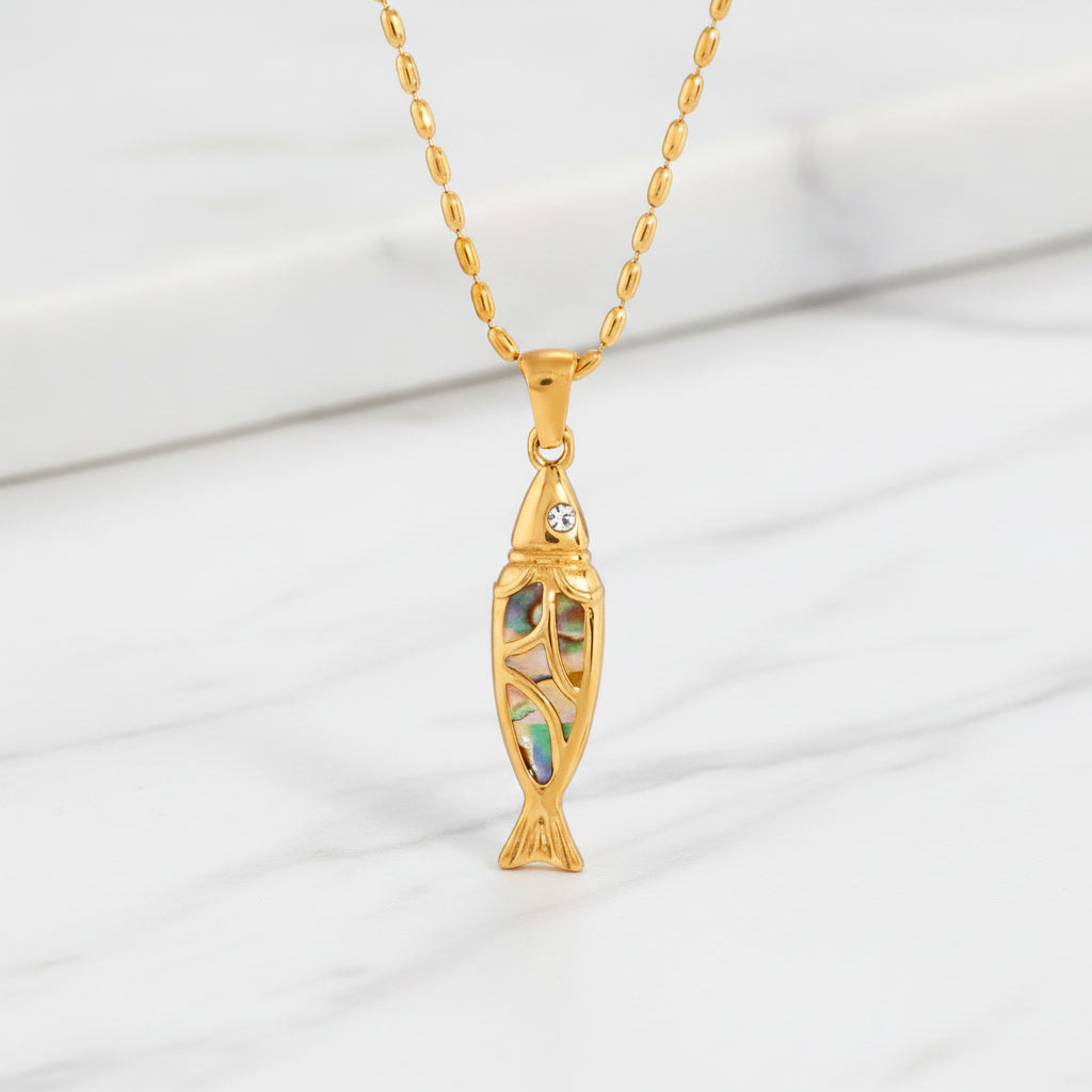 Elegant Esta Abalone gemstone pendant on a luxurious gold necklace, placed on a white marble surface.
