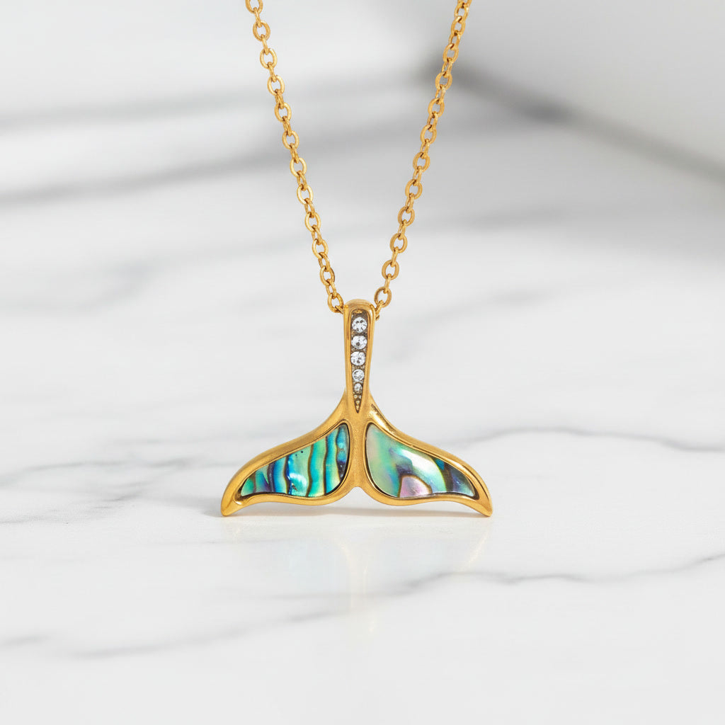 Luxury gold necklace featuring an abalone gemstone from Esta, displayed on a white marble surface with a sleek, polished finish.